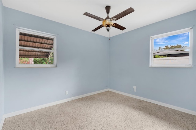 spare room featuring ceiling fan, speckled floor, a wealth of natural light, and baseboards