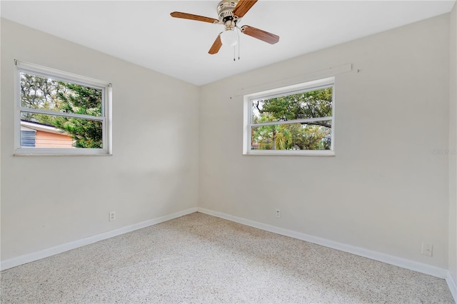 spare room with ceiling fan, baseboards, and speckled floor