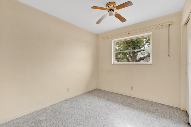 empty room with ceiling fan, speckled floor, and baseboards