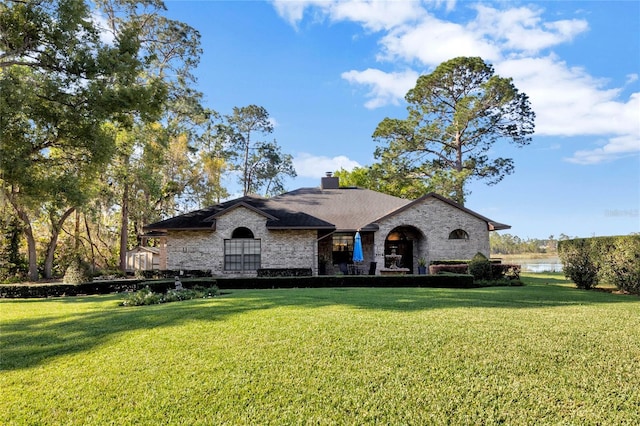 view of front of home with a chimney, a front yard, and a water view