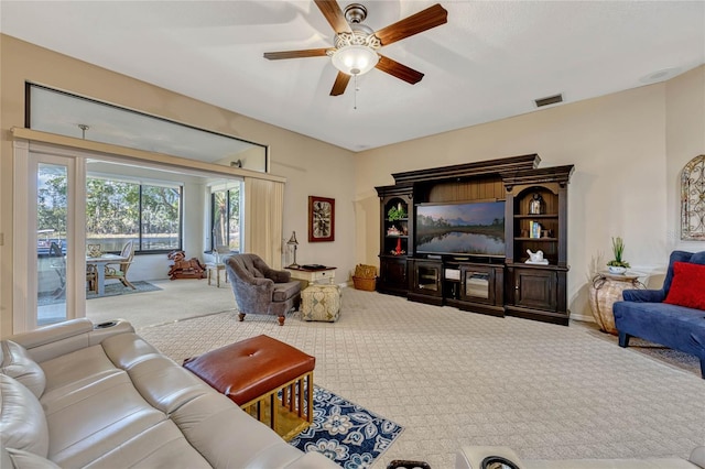 living area with visible vents, baseboards, a ceiling fan, and carpet flooring