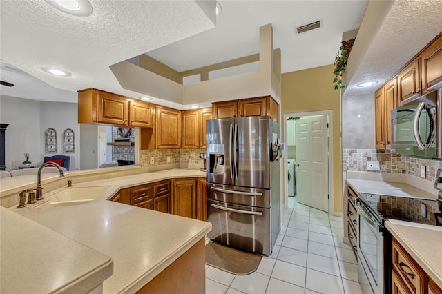 kitchen with visible vents, a sink, open floor plan, appliances with stainless steel finishes, and light countertops