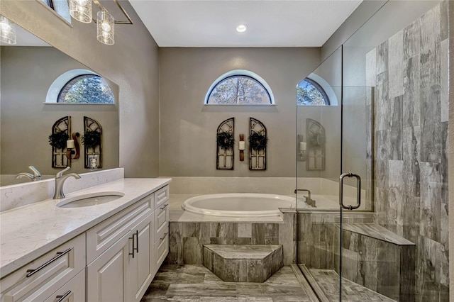 bathroom with a shower stall, a bath, and vanity