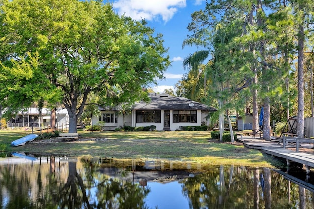 back of house featuring a water view and a lawn