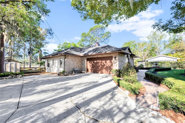 view of front of property with cooling unit, driveway, a chimney, an outdoor structure, and a garage