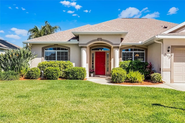 single story home with a garage, stucco siding, a shingled roof, and a front lawn