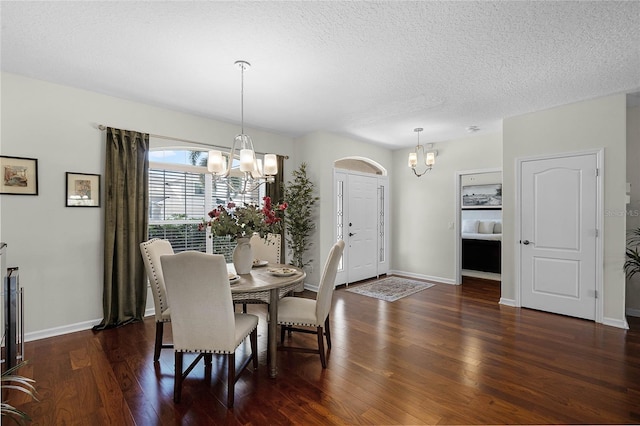 dining space with dark wood finished floors, a textured ceiling, baseboards, and a chandelier