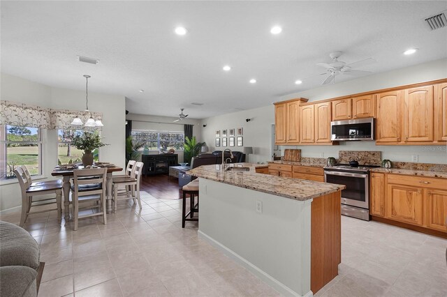 kitchen featuring stainless steel appliances, visible vents, open floor plan, and ceiling fan with notable chandelier