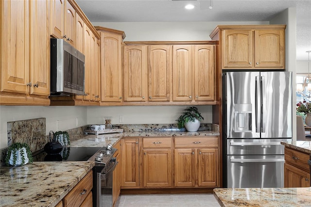 kitchen with light stone counters, recessed lighting, a textured ceiling, and stainless steel appliances