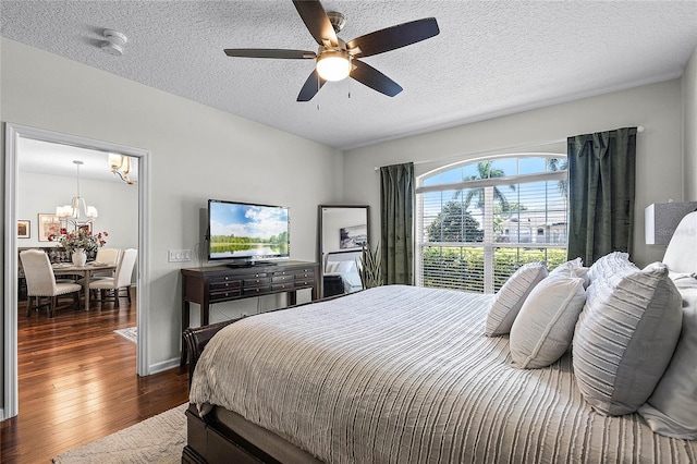 bedroom with dark wood finished floors, ceiling fan with notable chandelier, and a textured ceiling