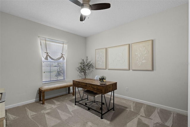 carpeted office with a textured ceiling, baseboards, and a ceiling fan