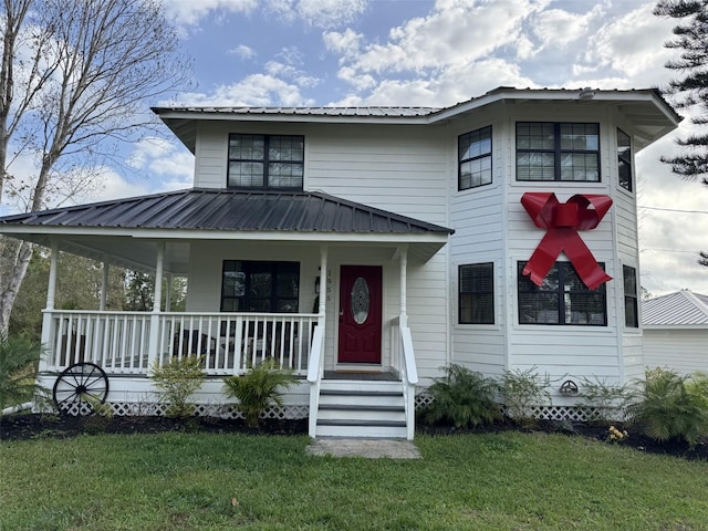 view of front of property with a porch, a front yard, and metal roof