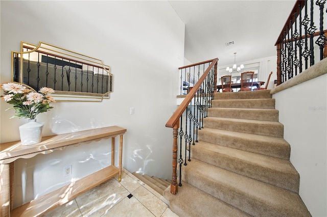 staircase featuring tile patterned floors, visible vents, and a notable chandelier