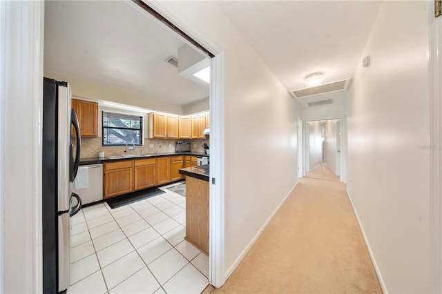 corridor with visible vents, attic access, light tile patterned flooring, a sink, and light colored carpet