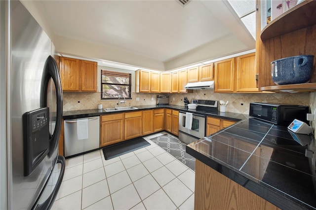 kitchen with light tile patterned floors, a sink, stainless steel appliances, under cabinet range hood, and backsplash