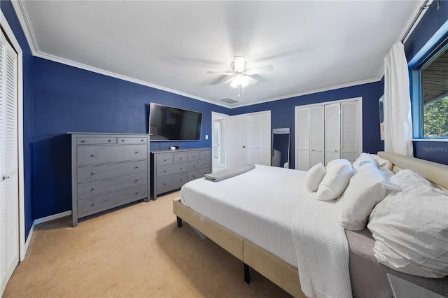 carpeted bedroom with visible vents, multiple closets, ornamental molding, a ceiling fan, and baseboards