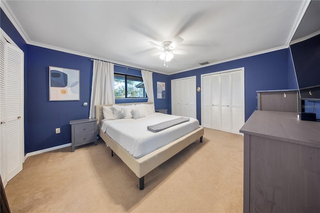 bedroom with visible vents, light carpet, two closets, and crown molding