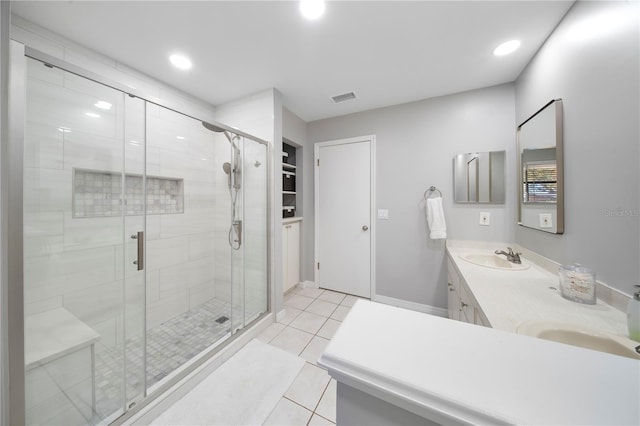 bathroom featuring visible vents, a shower stall, double vanity, tile patterned floors, and a sink