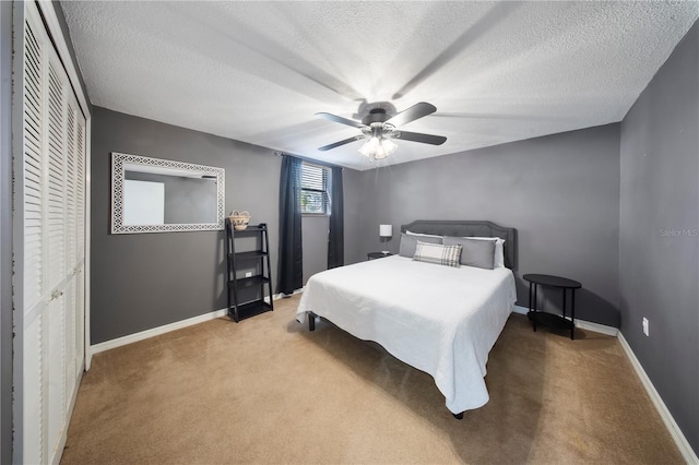 bedroom featuring a textured ceiling, a closet, carpet flooring, baseboards, and ceiling fan