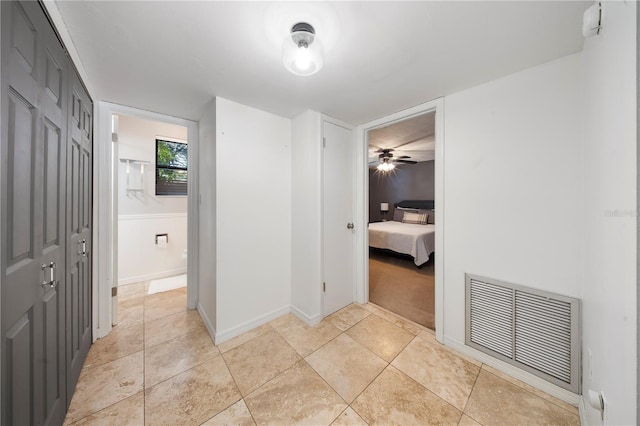 hallway featuring light tile patterned floors, visible vents, and baseboards