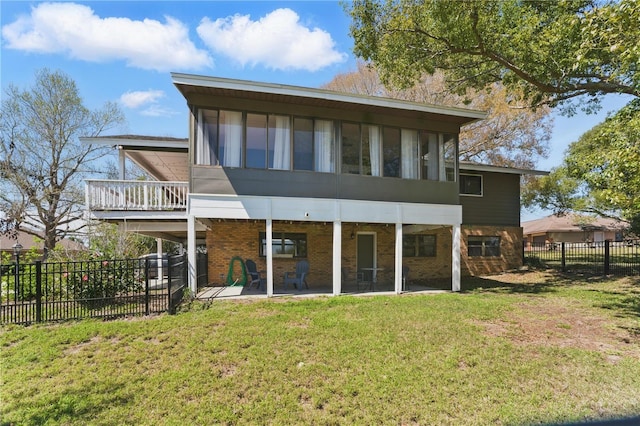 back of house featuring a fenced backyard, brick siding, a sunroom, a patio area, and a lawn