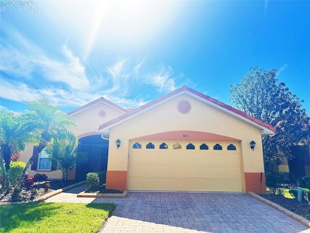 mediterranean / spanish-style home featuring decorative driveway, a garage, and stucco siding