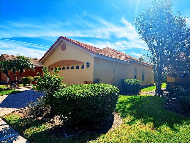 view of property exterior with a tiled roof, an attached garage, and stucco siding