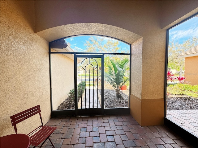 exterior space featuring brick floor and a textured wall