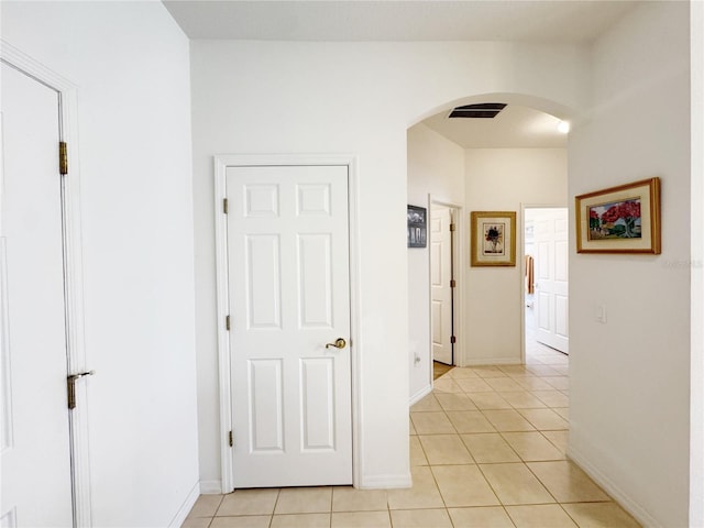 corridor with light tile patterned floors, visible vents, arched walkways, and baseboards