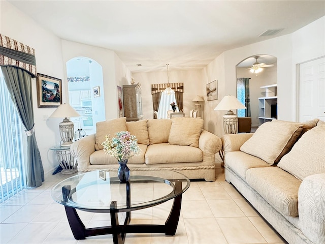 living area featuring light tile patterned floors, arched walkways, and plenty of natural light