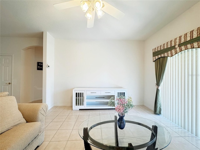 living room with light tile patterned floors, arched walkways, baseboards, and a ceiling fan