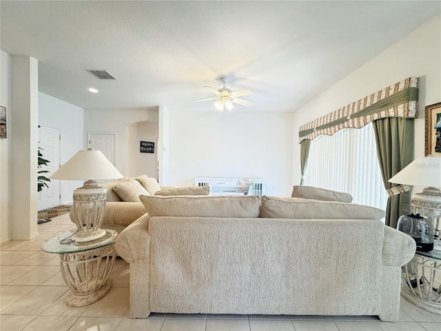 living area with light tile patterned floors, arched walkways, visible vents, and ceiling fan