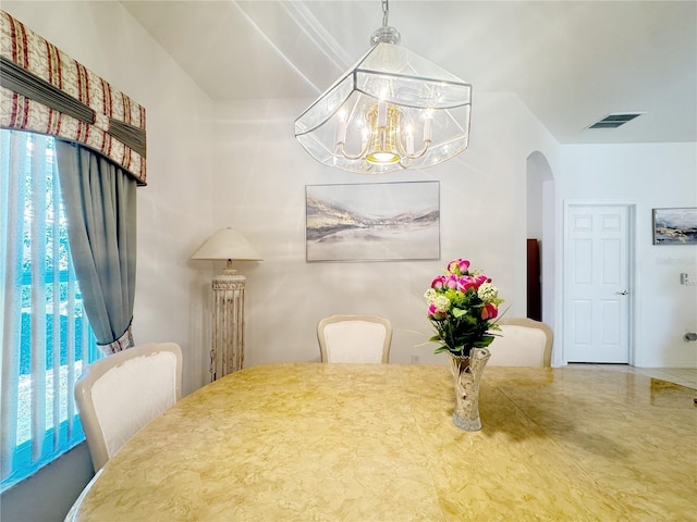 dining room with arched walkways, visible vents, and a notable chandelier