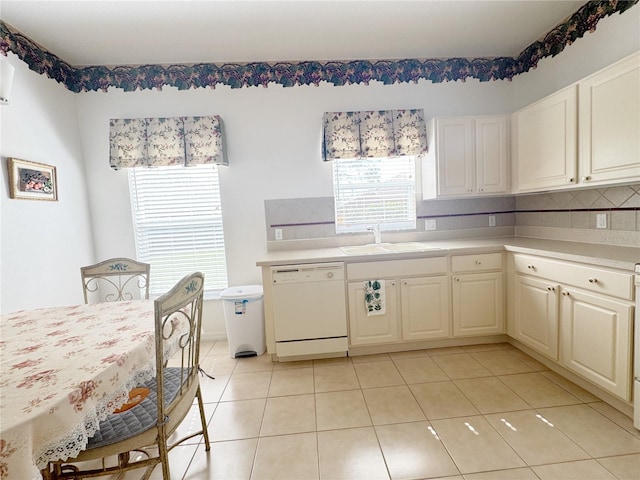 kitchen with a sink, tasteful backsplash, white dishwasher, and light countertops