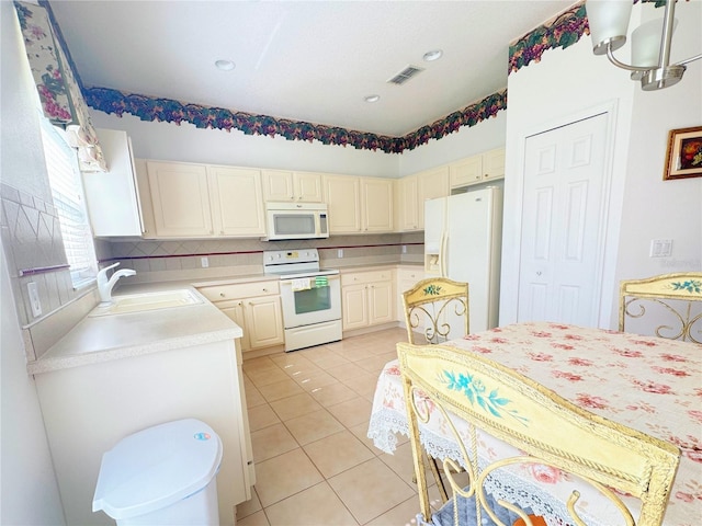 kitchen featuring white appliances, visible vents, light tile patterned flooring, a sink, and light countertops