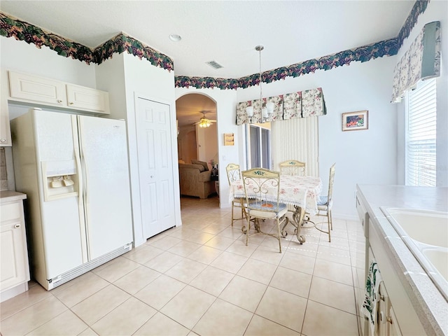 dining area featuring arched walkways, visible vents, a ceiling fan, and light tile patterned flooring