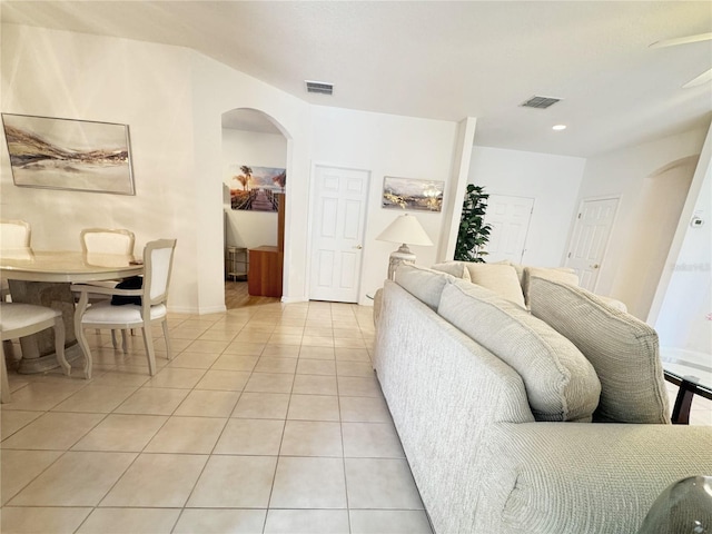 living area with arched walkways, light tile patterned floors, and visible vents