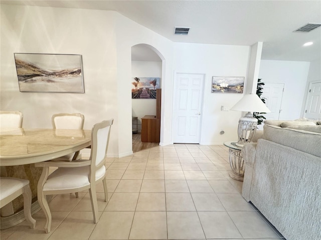 dining space featuring light tile patterned floors, visible vents, arched walkways, and baseboards