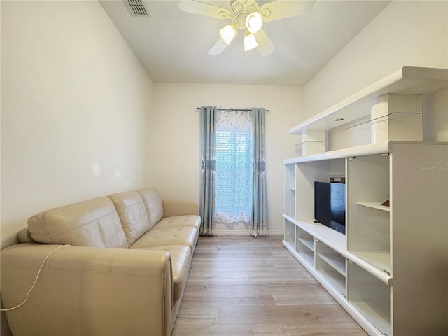 living room with baseboards, a ceiling fan, visible vents, and light wood-type flooring