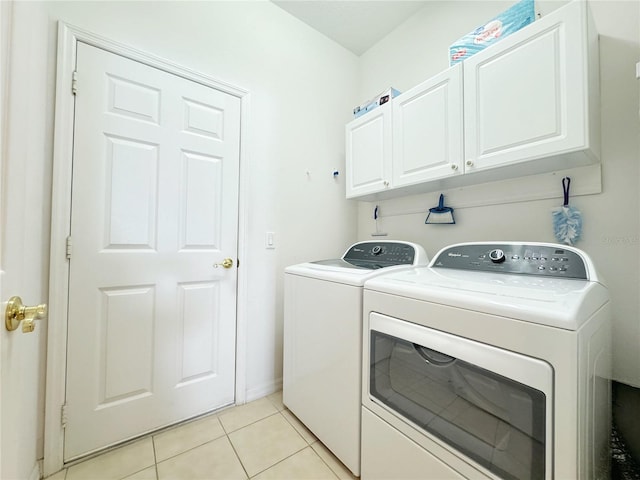 clothes washing area featuring cabinet space, light tile patterned floors, washer and dryer, and baseboards