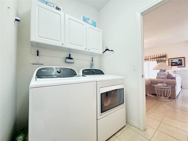 washroom with baseboards, cabinet space, washing machine and dryer, and light tile patterned flooring