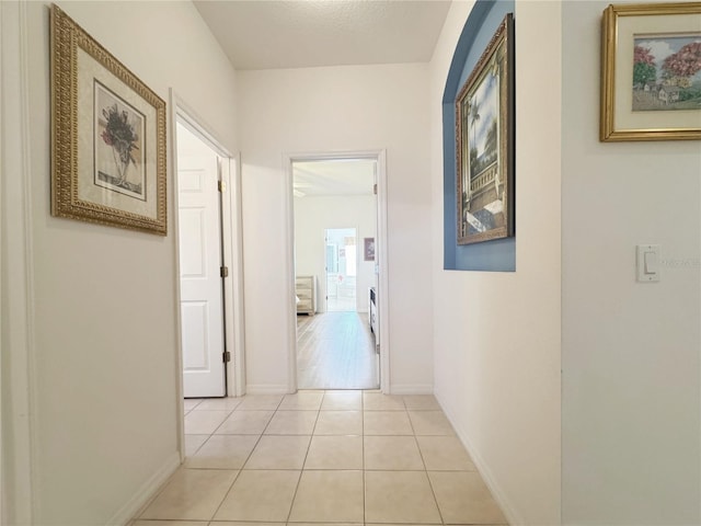 hall featuring light tile patterned floors and baseboards