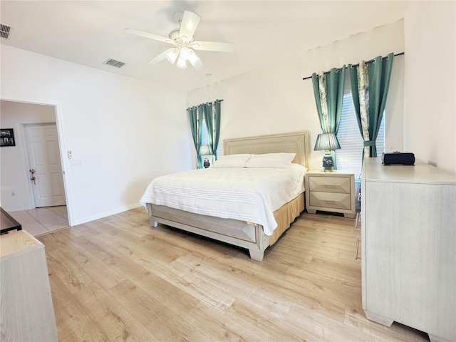 bedroom with visible vents, multiple windows, light wood-style floors, and baseboards