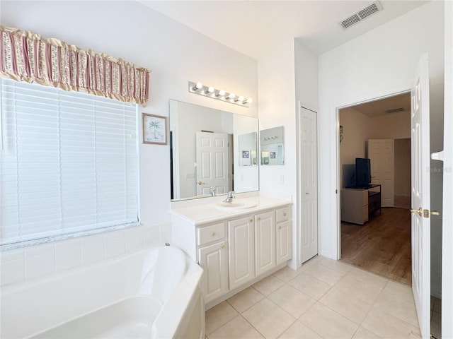 bathroom featuring tile patterned flooring, a bath, vanity, and visible vents