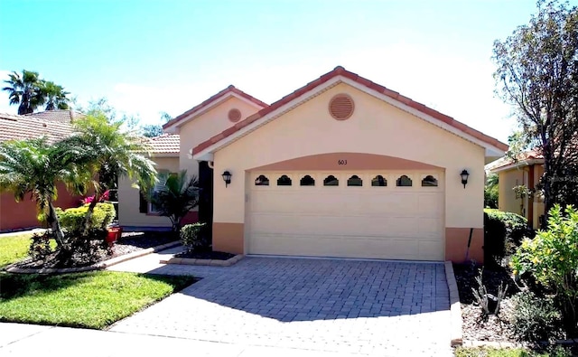 mediterranean / spanish house with stucco siding, a tile roof, decorative driveway, and a garage