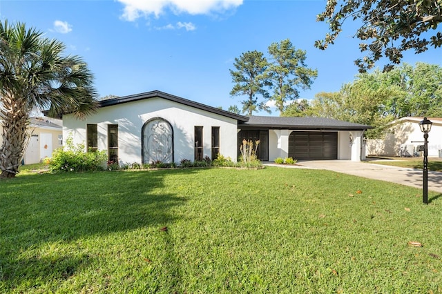 view of front of property with stucco siding, driveway, a front lawn, and a garage