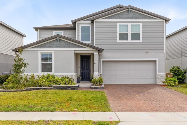 craftsman-style home featuring stone siding, an attached garage, decorative driveway, and a front lawn