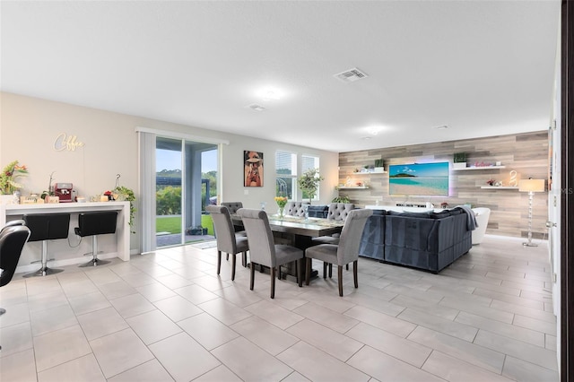 dining area featuring visible vents, an accent wall, and wooden walls