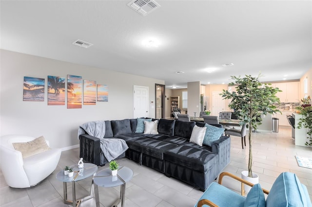 living area with light tile patterned floors, baseboards, and visible vents