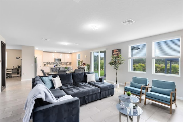 living room with light tile patterned flooring, visible vents, and baseboards